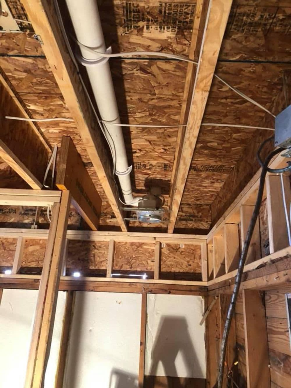 Interior construction showing exposed wooden beams, plumbing, and electrical wiring.