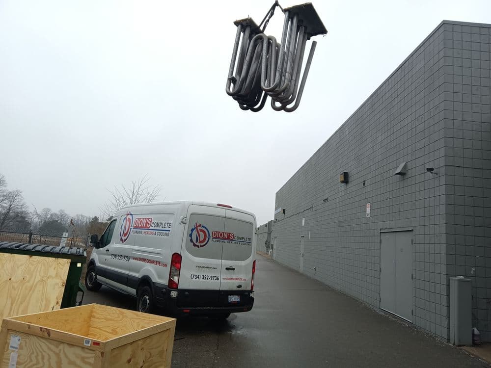 Dion's Complete truck parked near a building with lifting equipment overhead.