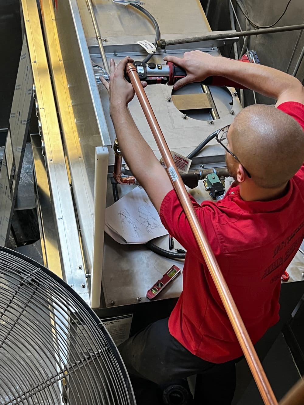 Technician installing copper pipe in HVAC system, ensuring airflow and efficiency.