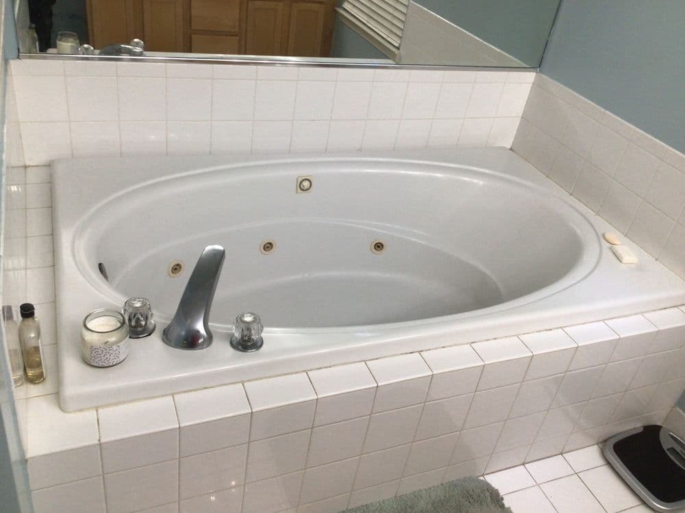 White jacuzzi tub with chrome fixtures and tiled surround in modern bathroom setting.