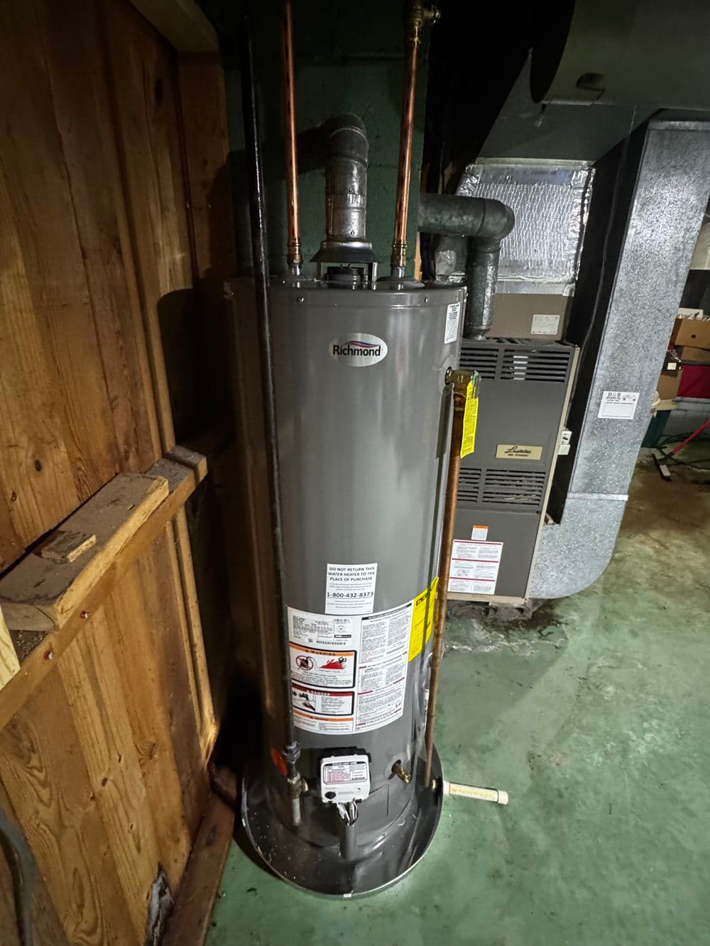 Richmond water heater installed in a basement with copper piping and ventilation system.