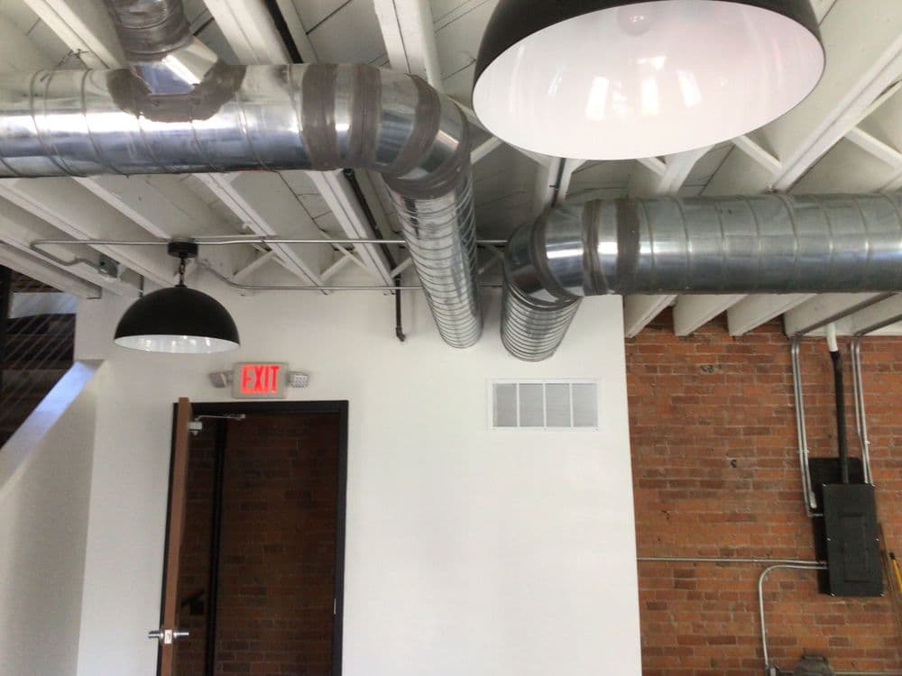 Industrial interior with exposed ductwork and hanging lights in a modern space.