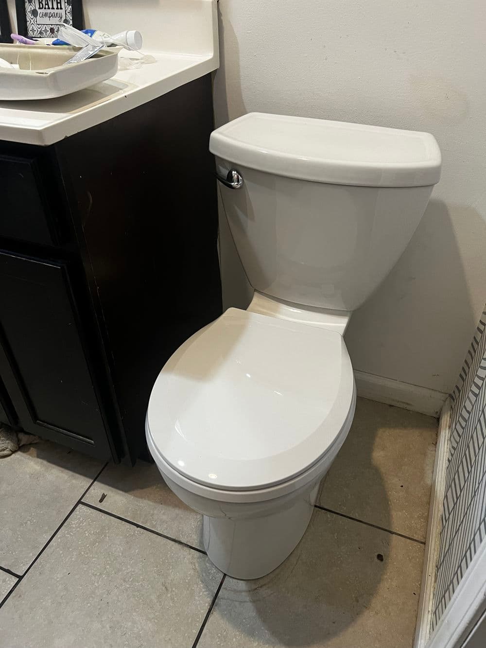 Modern white toilet in a bathroom setting with dark cabinetry and tiled floor.