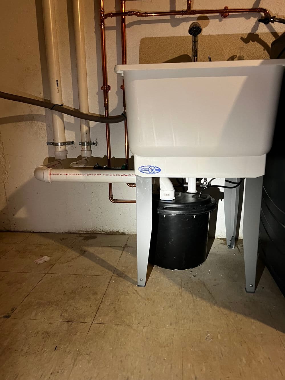 Utility sink with plumbing and drainage pipes in a basement setting.