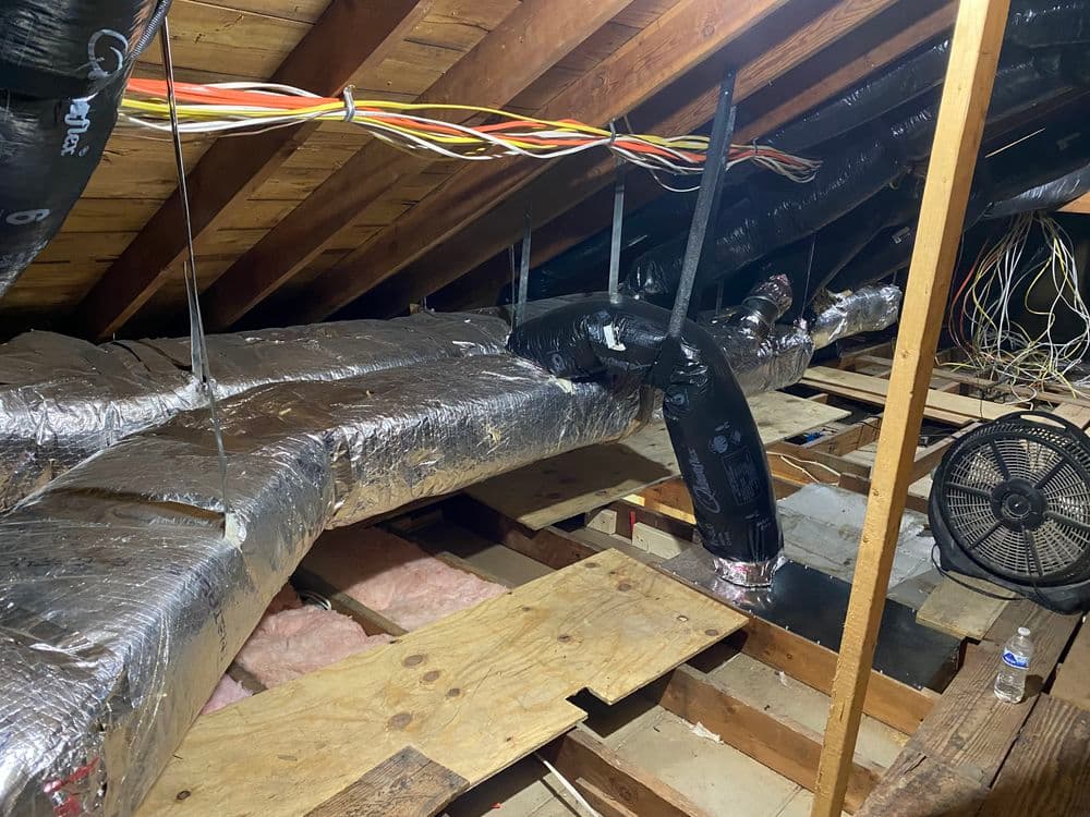 Insulated ductwork and electrical wiring in a residential attic space.