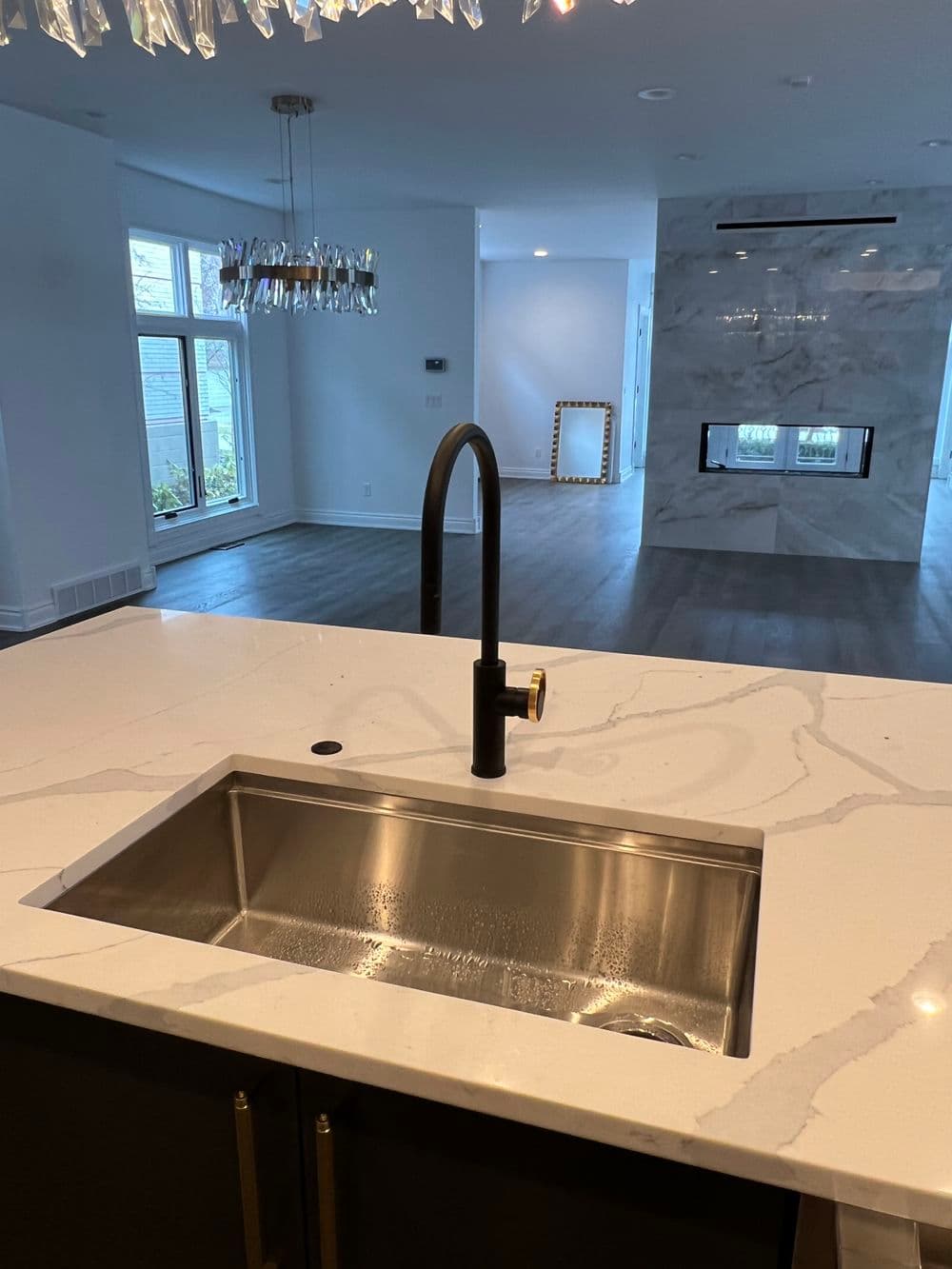 Modern kitchen with stainless steel sink and sleek black faucet, featuring marble accents.
