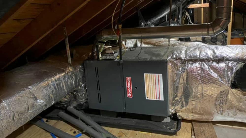 Goodman furnace installed in attic with insulated ductwork and ventilation pipes.