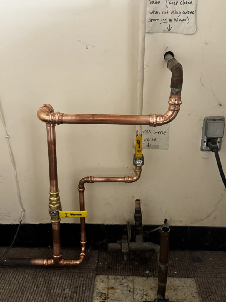 New copper water supply piping with shutoff valves on a basement wall