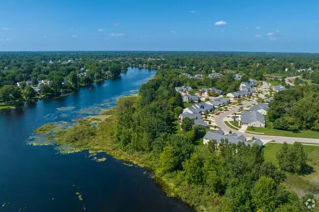 Aerial view of a lakeside neighborhood with homes along the shoreline and tree cover